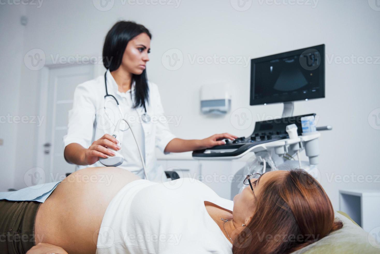 Female doctor does ultrasound for a pregnant woman in the hospital photo