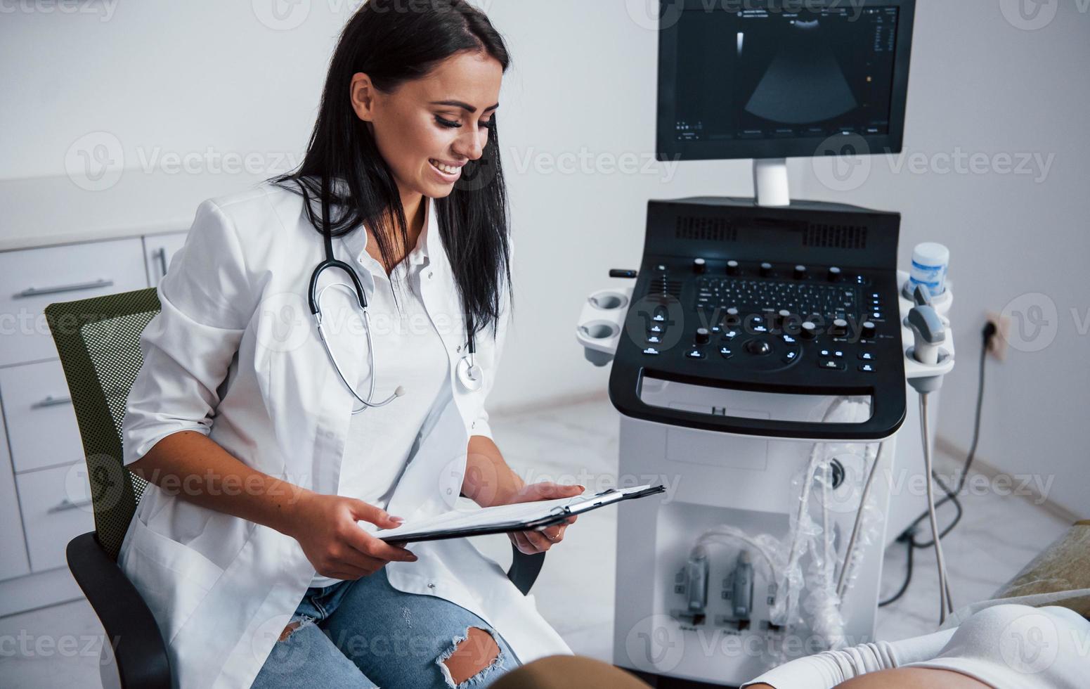 Portrait of obstetric doctor that sits in the clinic room with ultrasound device photo