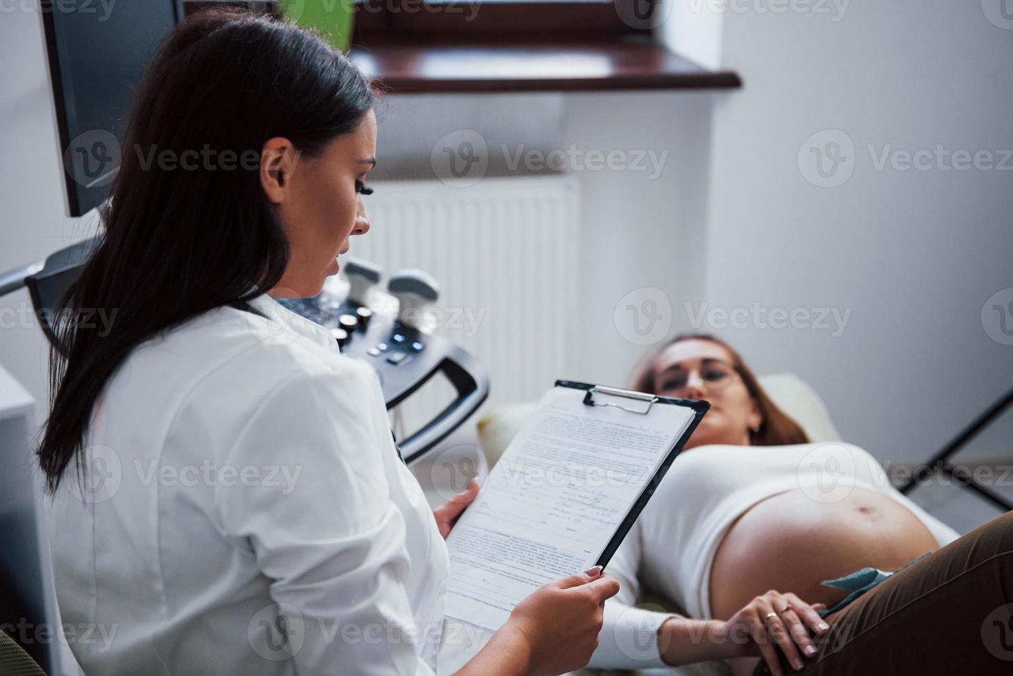 Female doctor talks about results of ultrasound for a pregnant woman in the hospital photo