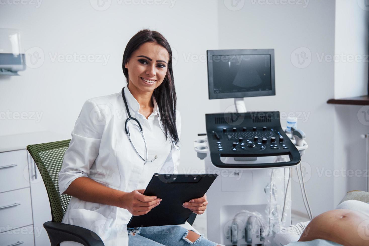 retrato de un médico obstetra que se sienta en la sala de la clínica con un dispositivo de ultrasonido foto