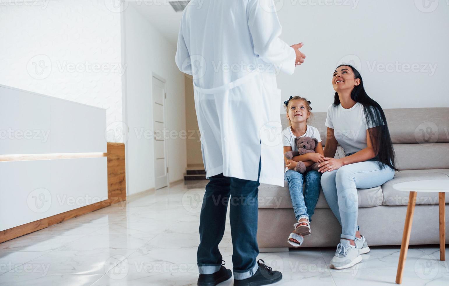 Mother with her cute daughter is visiting clinic. Listening to the doctor photo