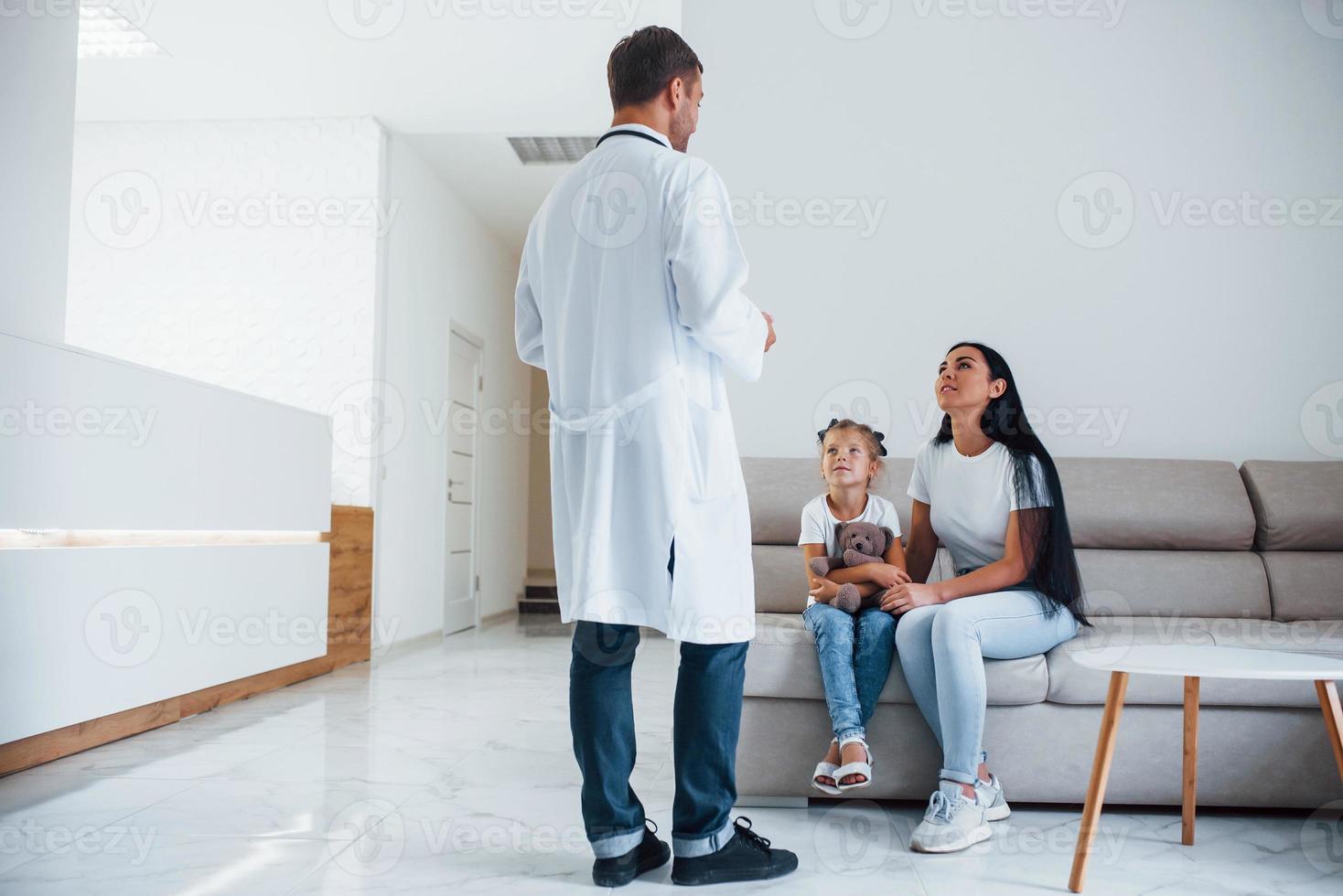 madre con su linda hija está visitando la clínica. escuchando al medico foto