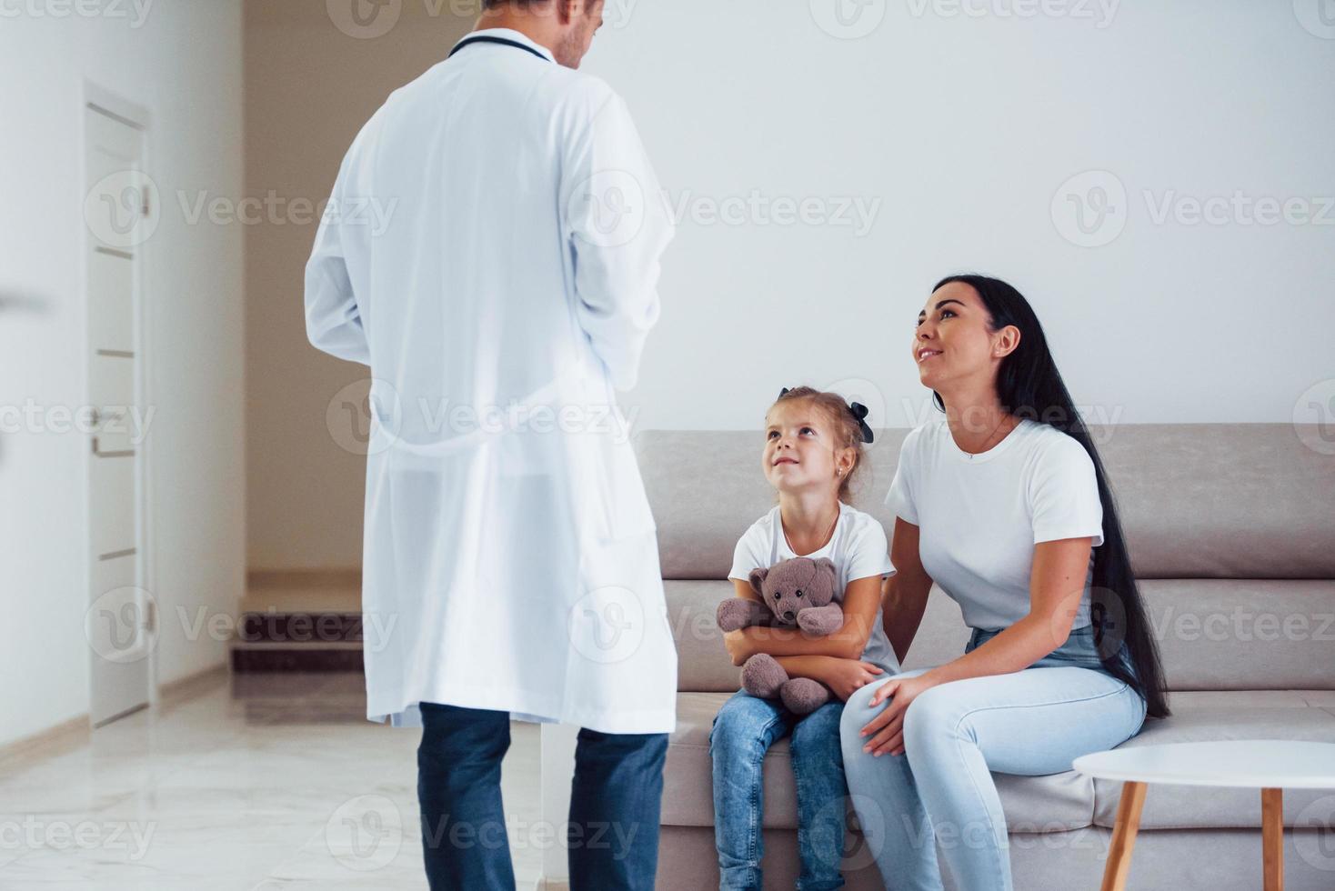 Mother with her cute daughter is visiting clinic. Listening to the doctor photo