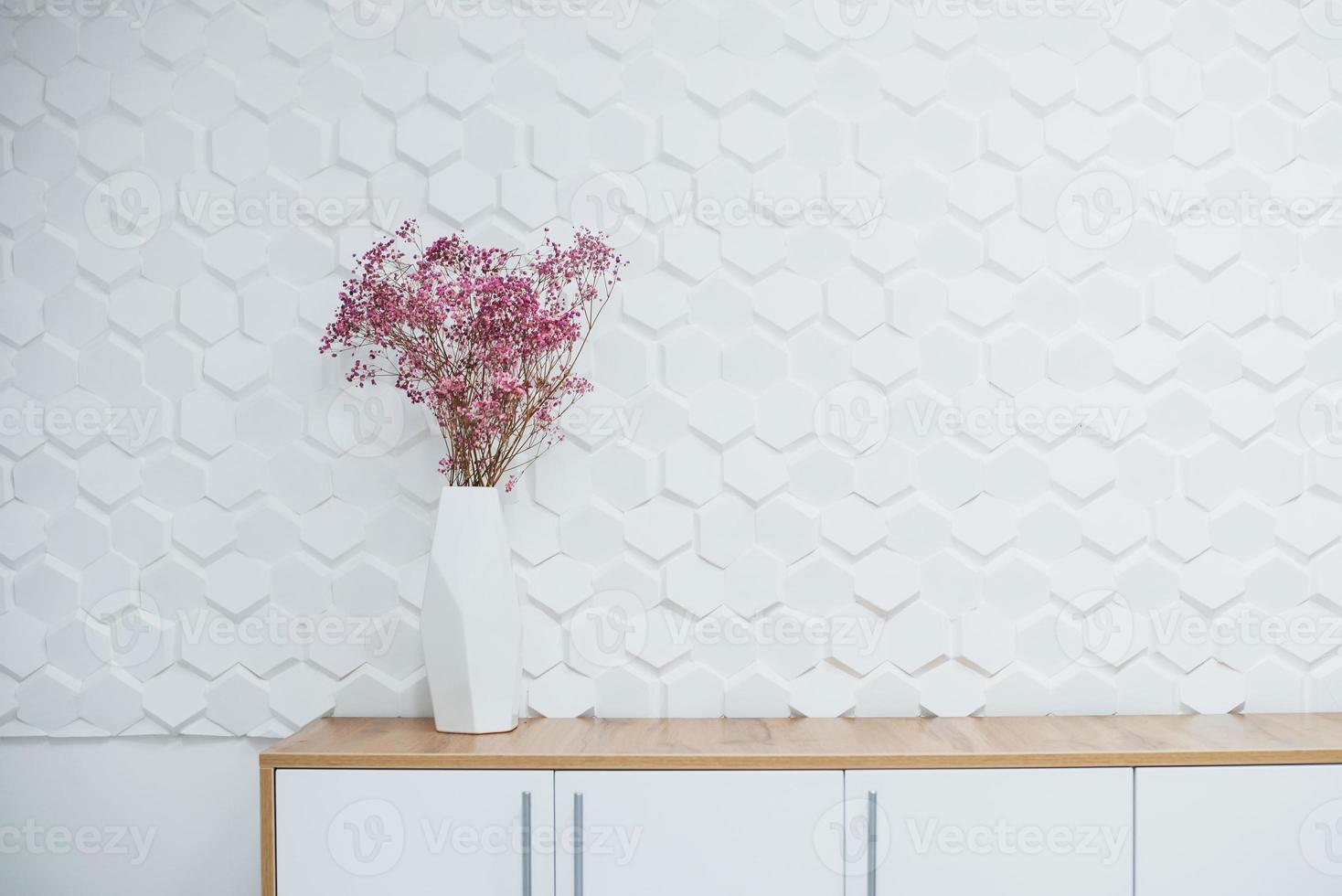 Simple interior of room with white textured walls and flowers on the table photo