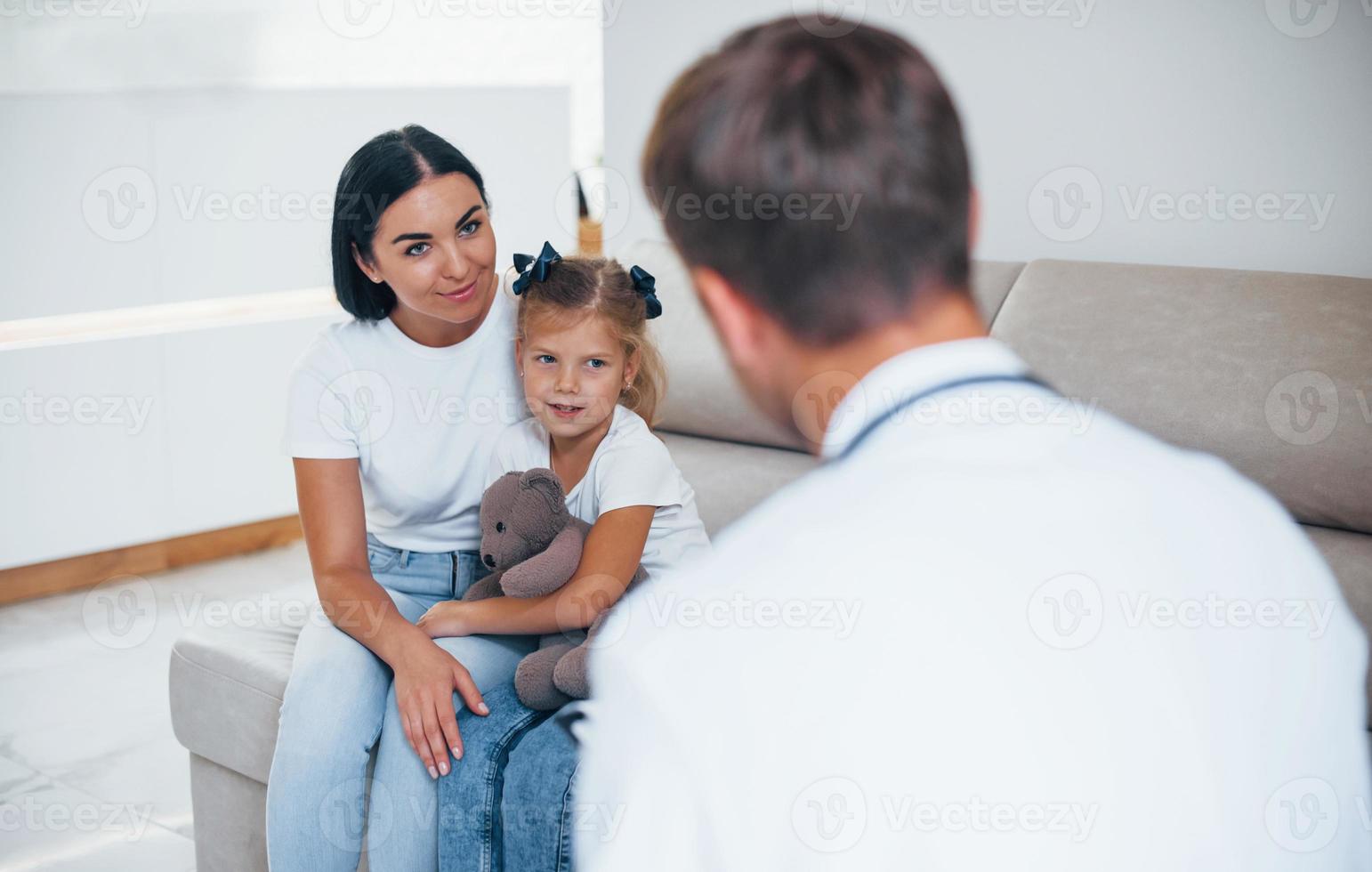 madre con su linda hija está visitando la clínica. escuchando al medico foto