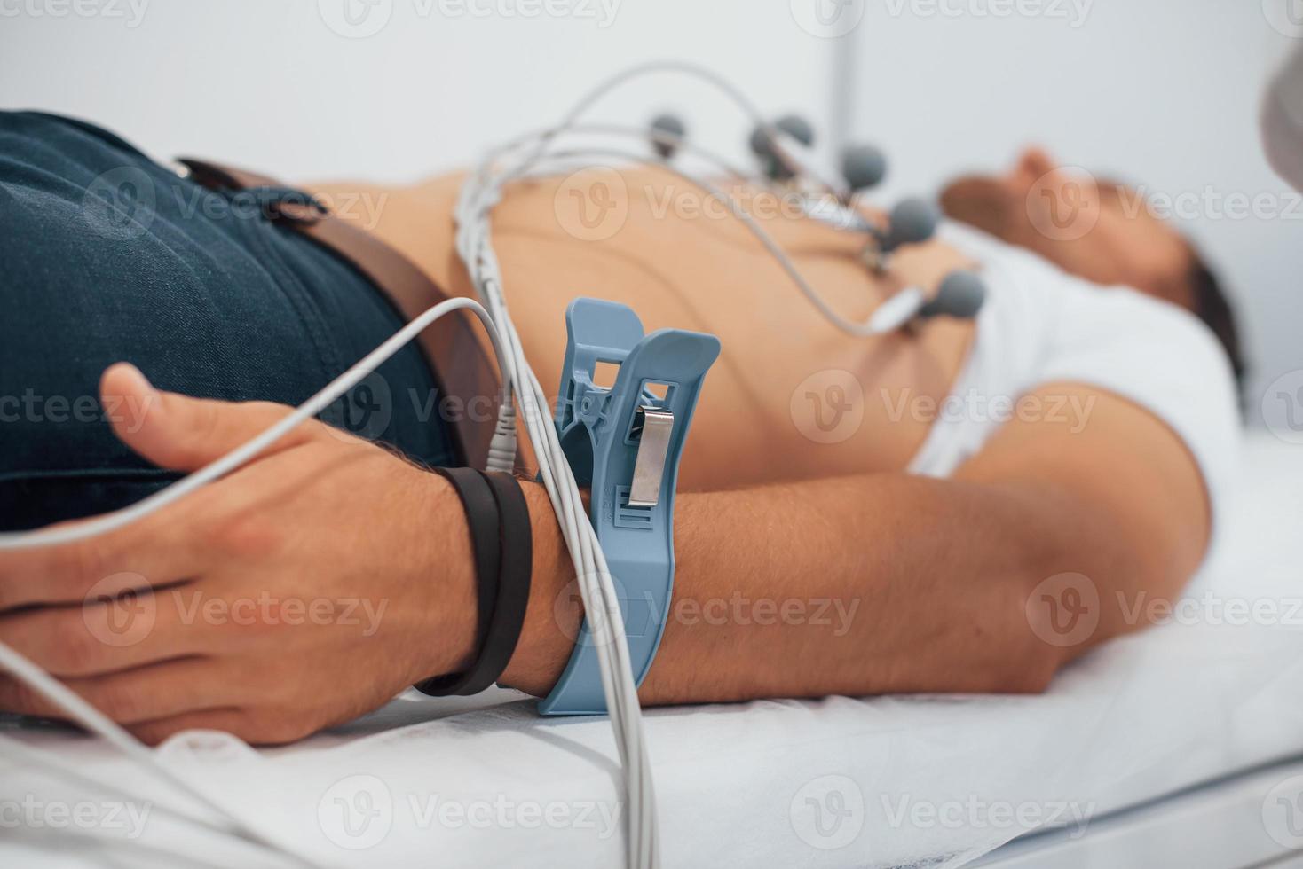 Man lying on the bed in the clinic and getting electrocardiogram test photo