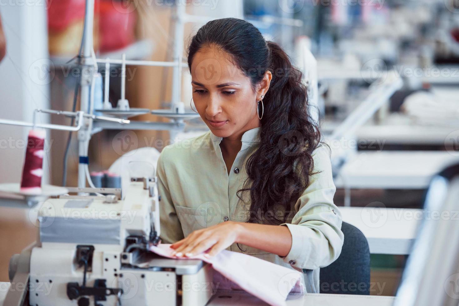 Mujer modista cose ropa en la máquina de coser en la fábrica
