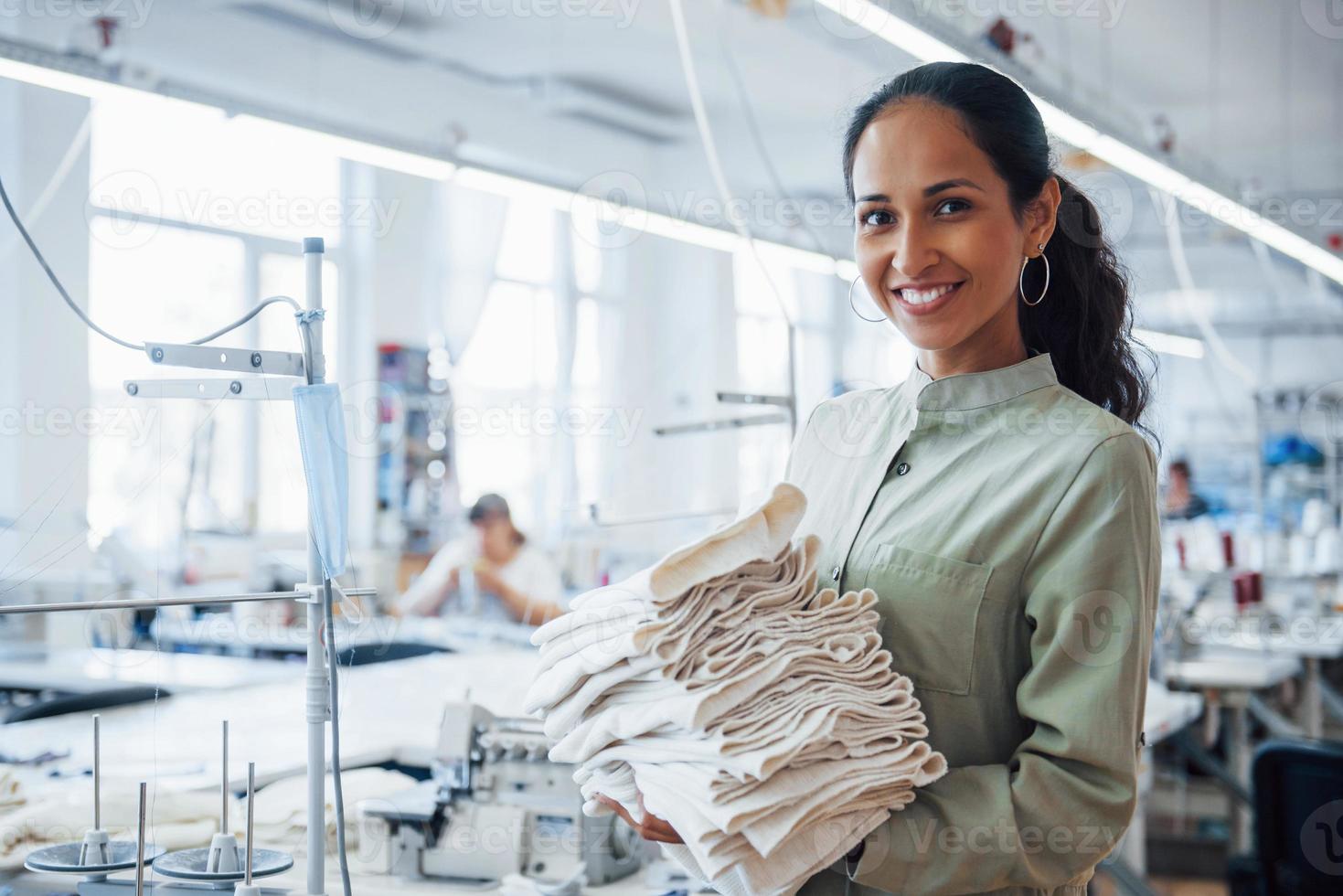 Woman dressmaker stands in the factory with cloth in hands 15227949