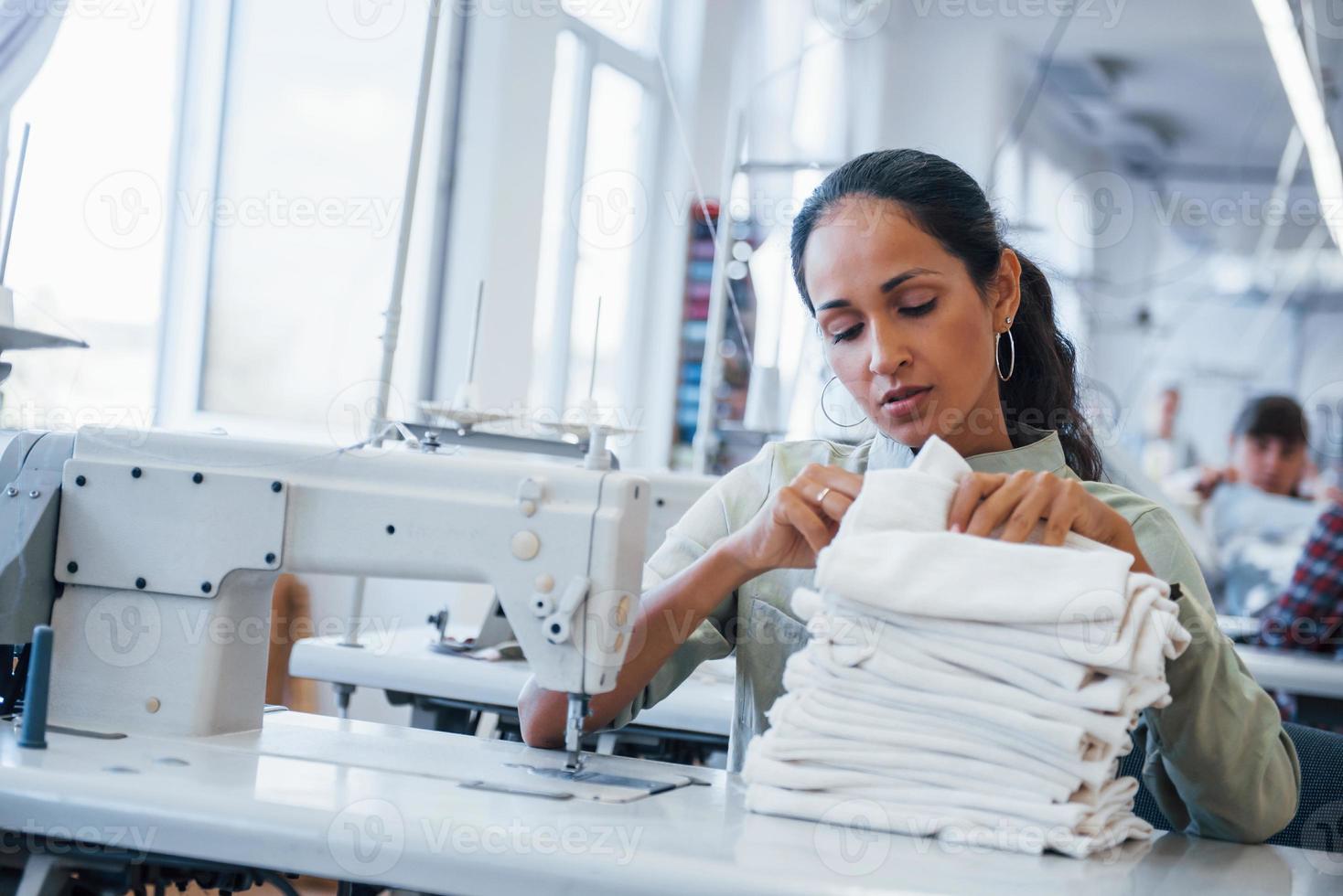 mujer modista cose ropa en la máquina de coser en la fábrica foto