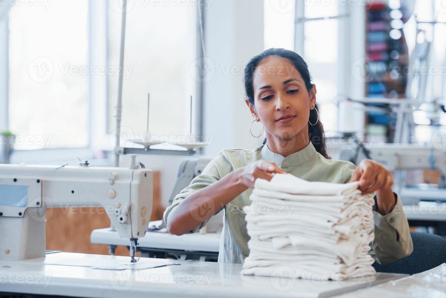 mujer modista cose ropa en la máquina de coser en la fábrica foto