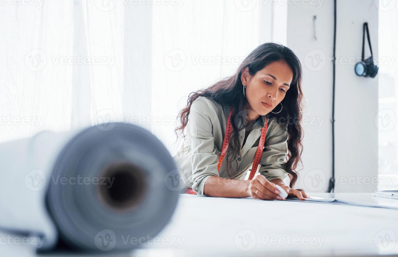 Cuts cloth. Beautiful female worker is in the sewing factory photo