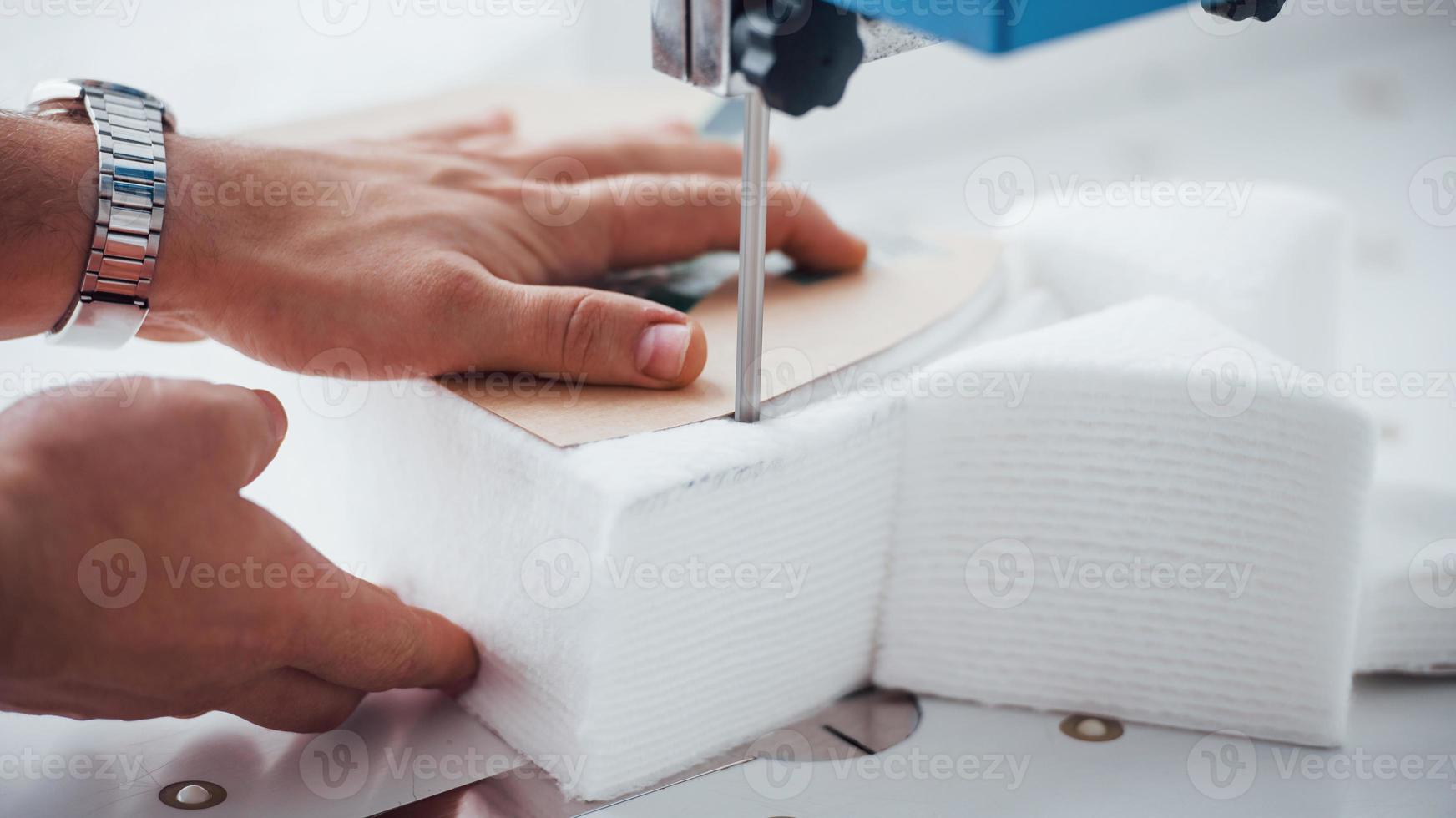 Detailed view of dressmaker woman sews clothes on sewing machine in factory photo