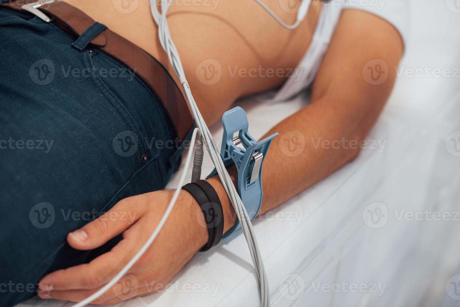 Man lying on the bed in the clinic and getting electrocardiogram test photo