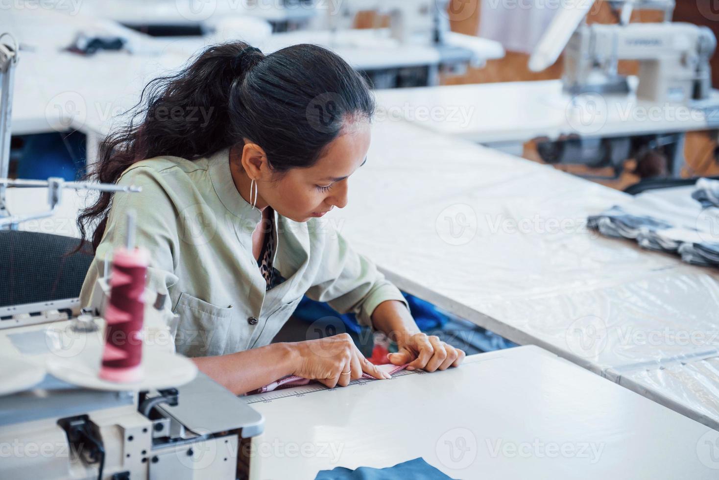 Mujer modista cose ropa en la máquina de coser en la fábrica