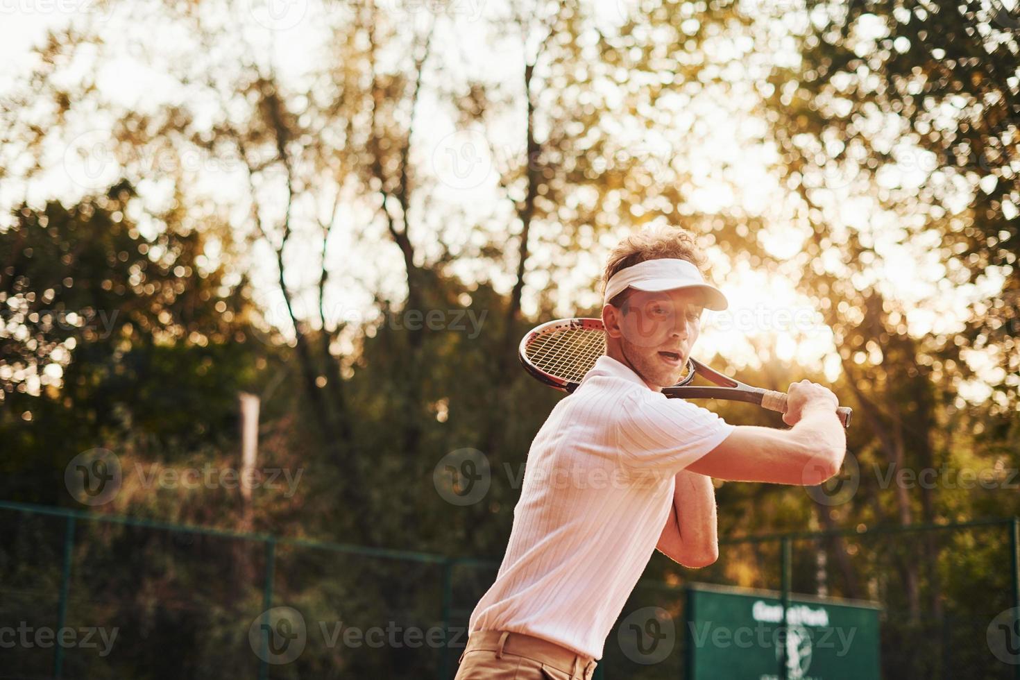 Photo in motion. Young tennis player in sportive clothes is on the court outdoors