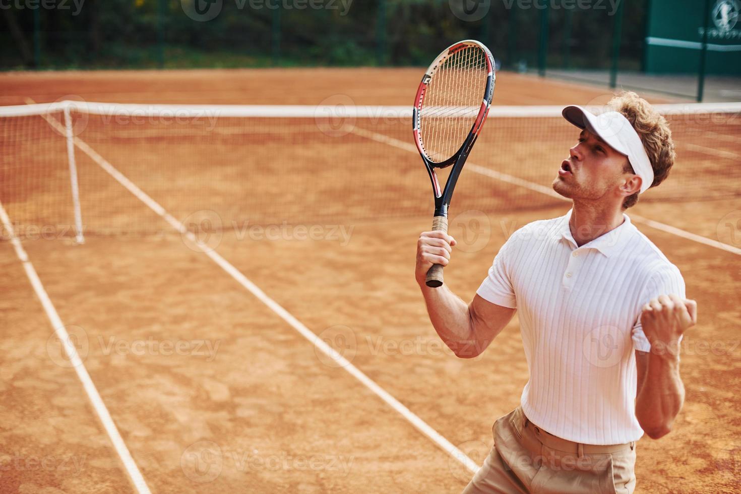 celebrando la victoria. joven tenista con ropa deportiva está en la cancha al aire libre foto