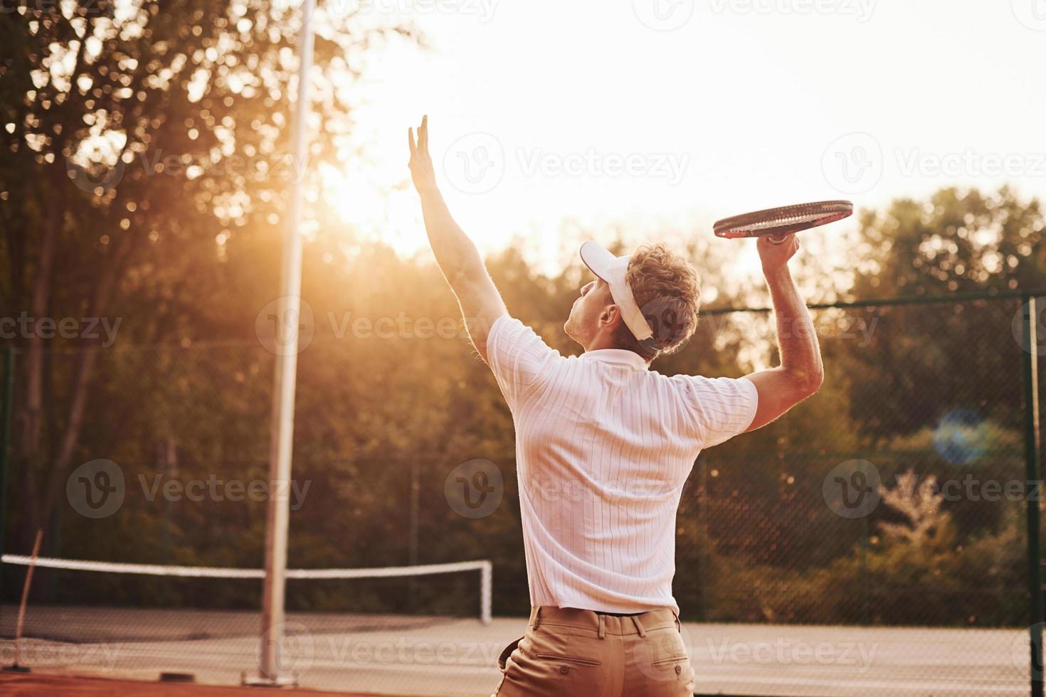 Young tennis player in sportive clothes is on the court outdoors photo