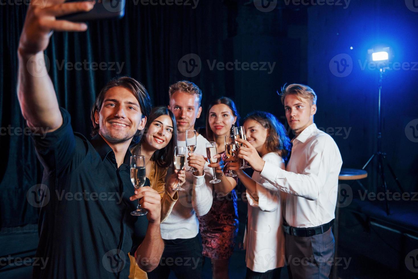 toma autofoto grupo de amigos alegres celebrando el año nuevo en el interior con bebidas en las manos foto