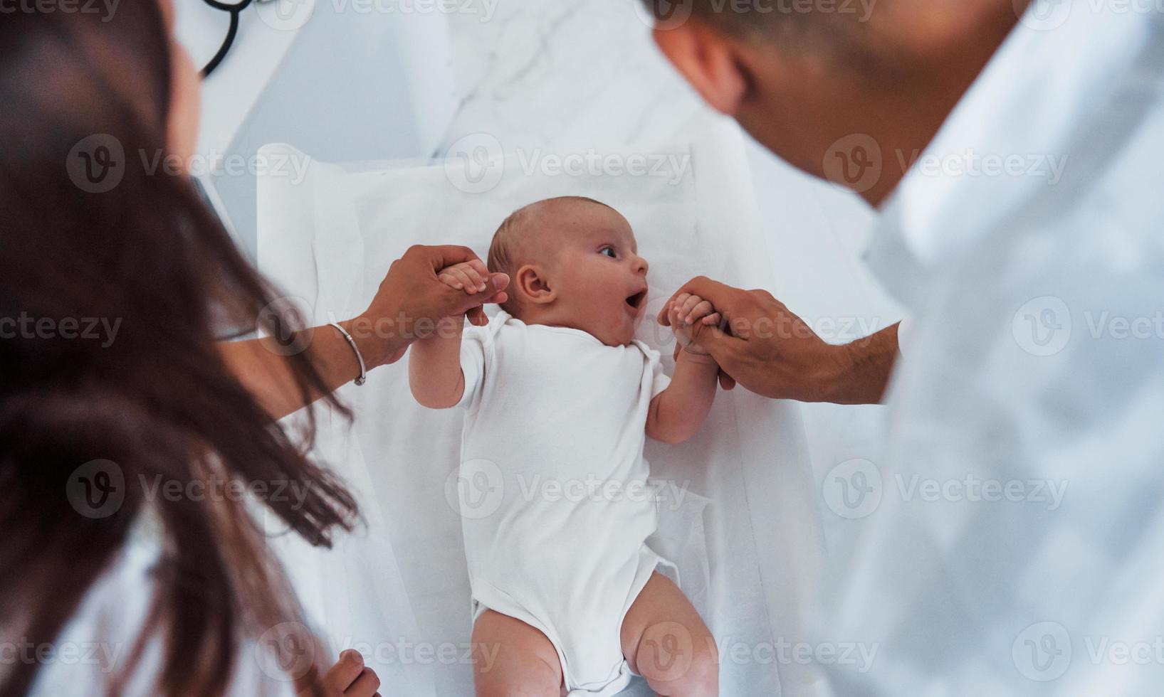 Young pediatrician is with little baby in the clinic at daytime photo