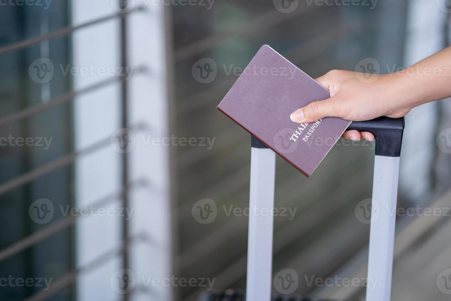 Close-up of young asian female tourist holding passport and boarding pass at airport photo