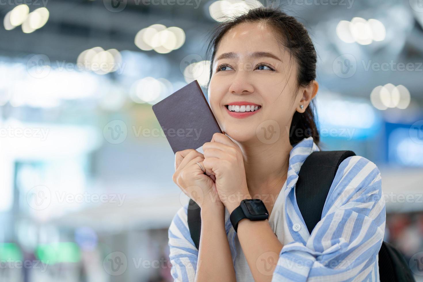 felicidad sonriente viajera asiática mostrando pasaporte en la terminal del aeropuerto. mujer asiática lista para viajar después del encierro en el aeropuerto foto