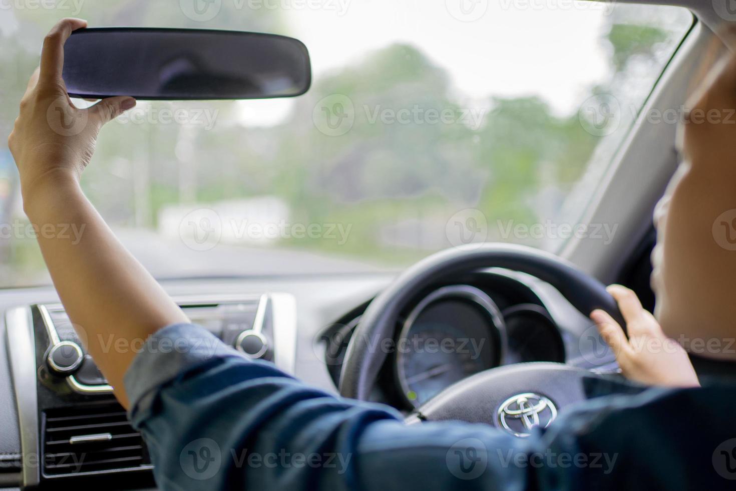 Young woman adjusting the rearview mirror in her car. Ensuring she has a clear view of her surroundings. photo