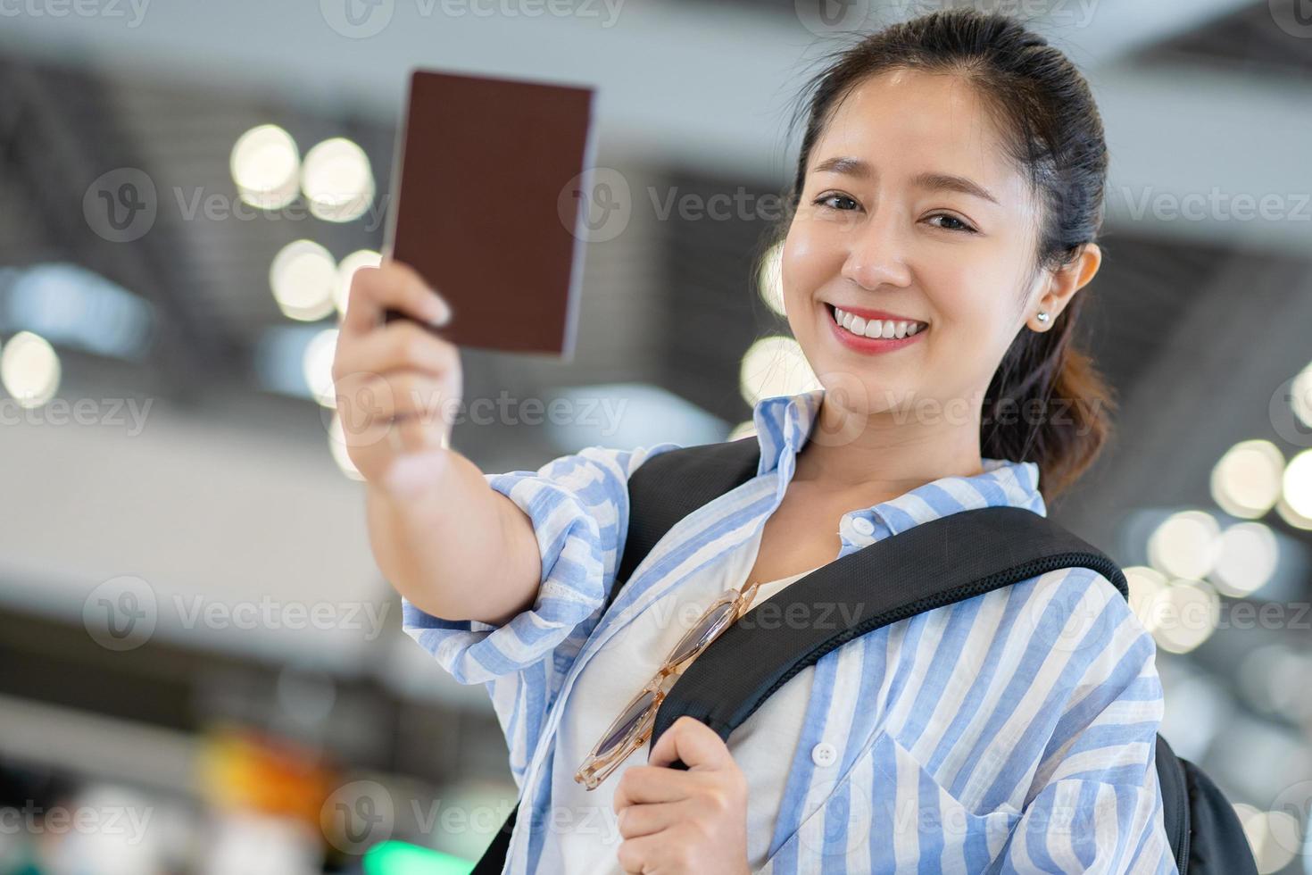 Young Asian female tourist at the airport on the weekend. She was happy and showed her passport in hand photo