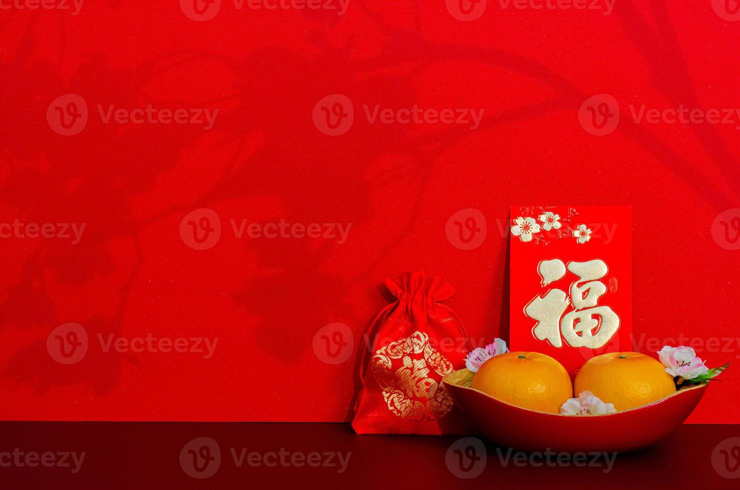 Red envelope packet or ang bao word mean wealth puts with oranges and red bag word is wealth with shadow of peach blossom on red glitter paper background. photo