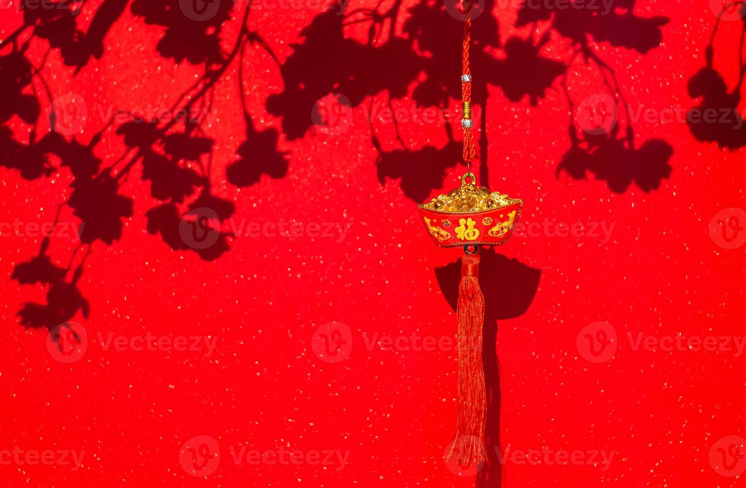 Hanging pendant word mean wealth for Chinese new year ornament with shadow of peach blossom flowers on red glitter paper background. photo