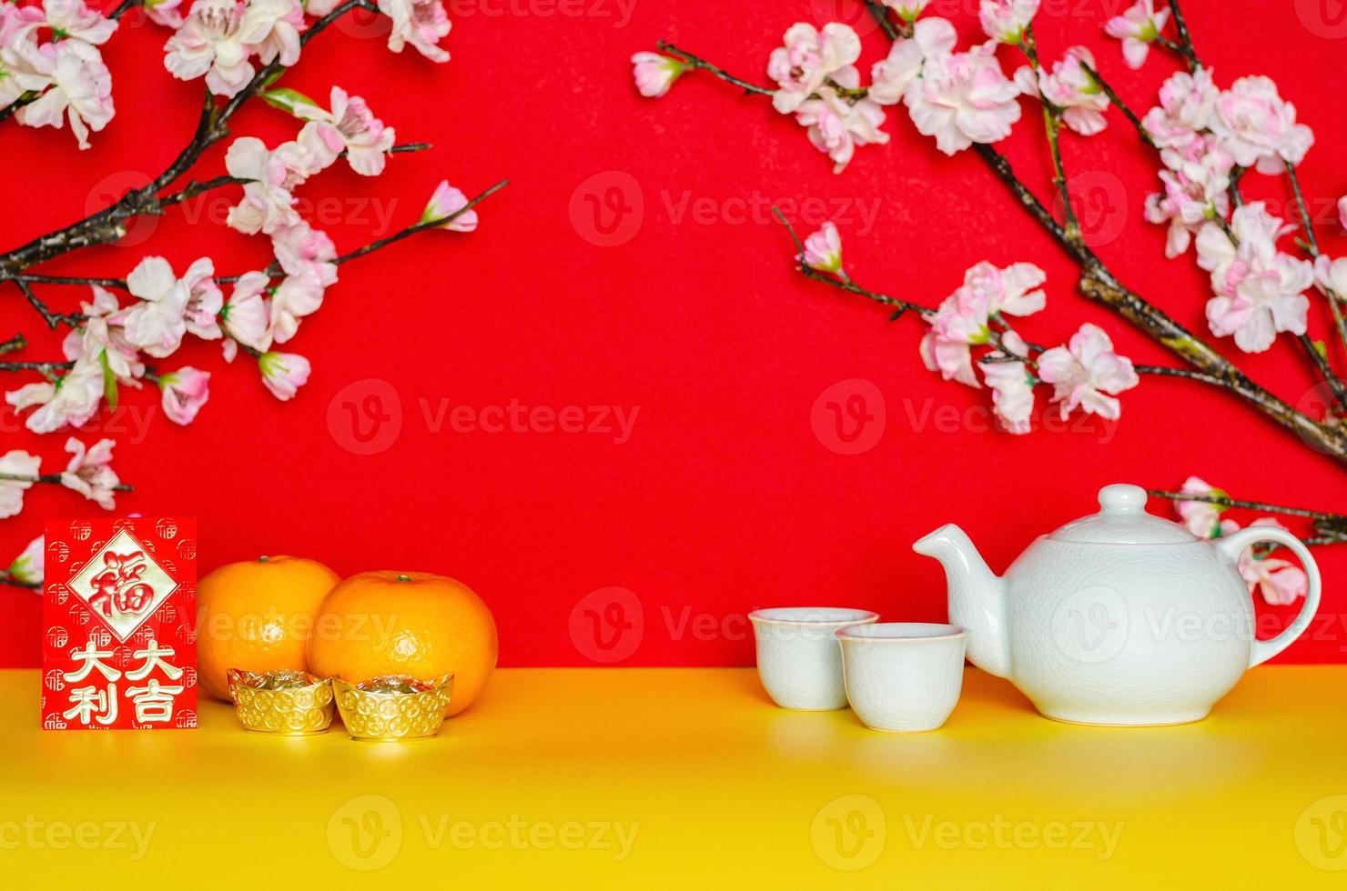 Tea set, oranges, ingots and red envelope packet or ang bao word mean great fortune with peach blossom on yellow and red glitter paper background. photo