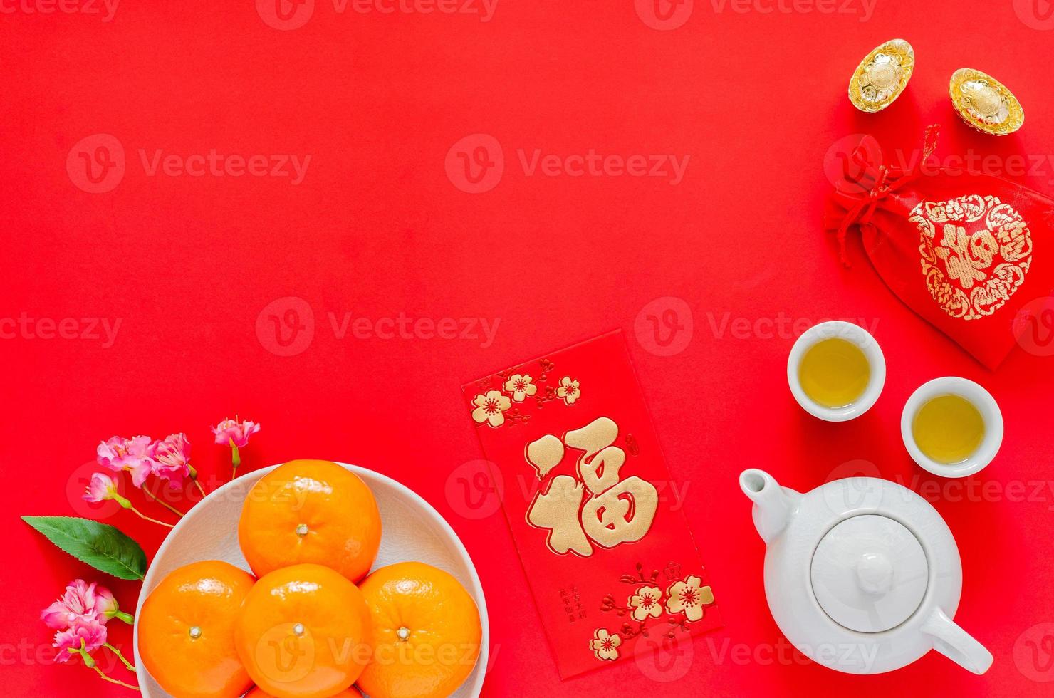 Chinese new year red background with gold ingots, red bag word mean wealth, tea set, red envelope packet or ang bao word means wealth, oranges and chinese blossom flowers. photo
