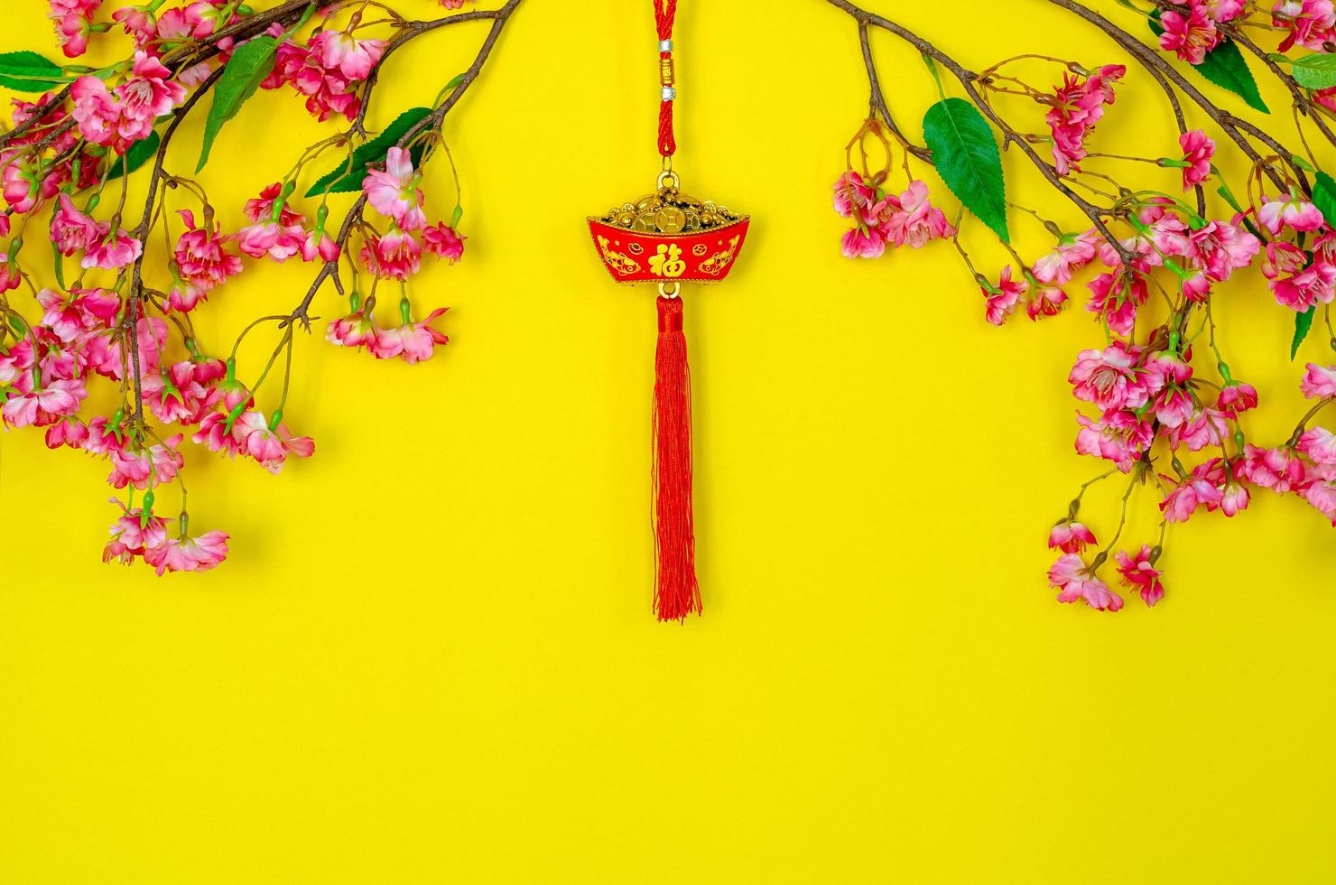 Hanging pendant for Chinese new year ornament meaning of word is wealth with Chinese blossom flowers on yellow background. photo