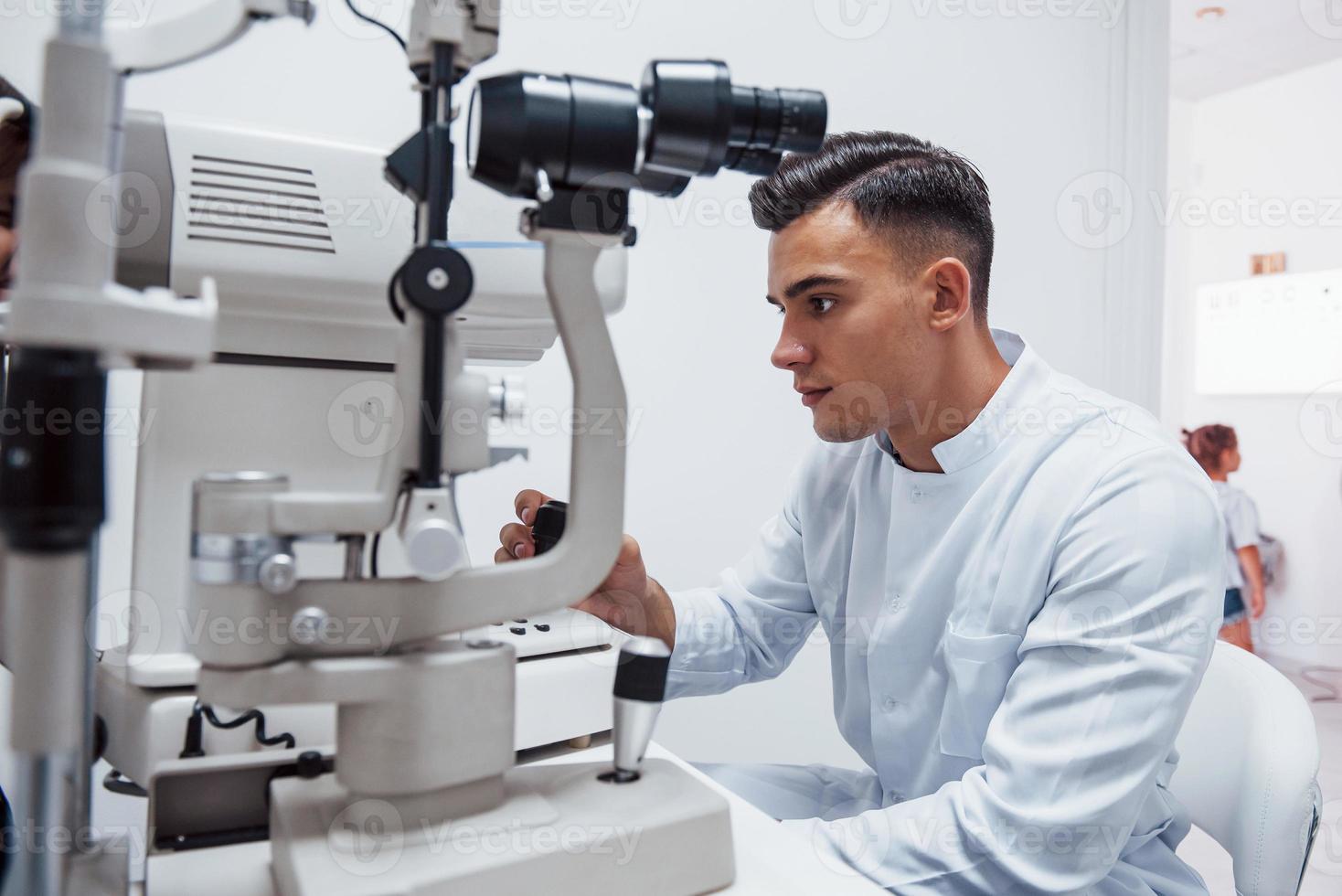 Oculist tests vision of patient by using special modern machine photo