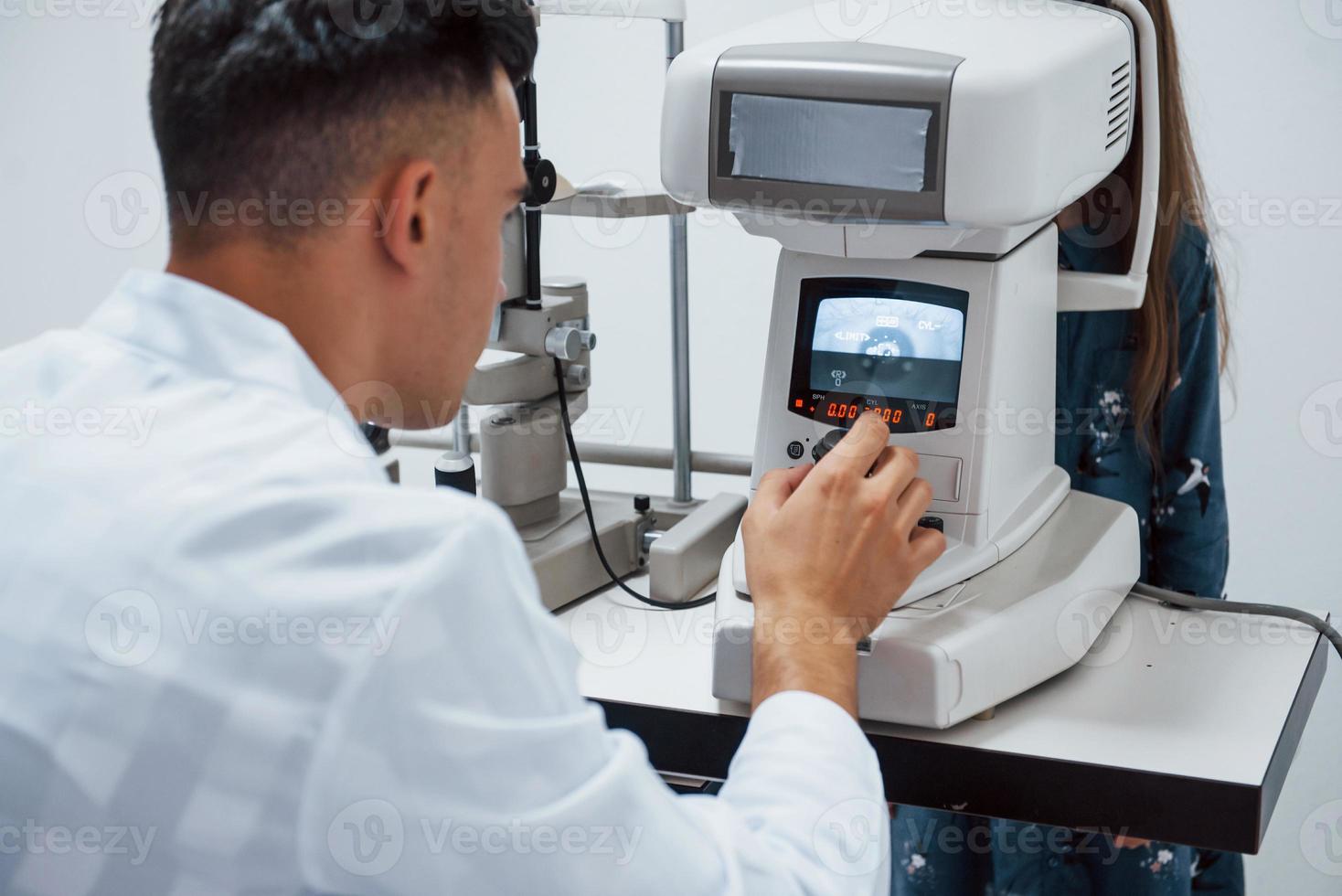 Oculist tests vision of patient by using special modern machine photo