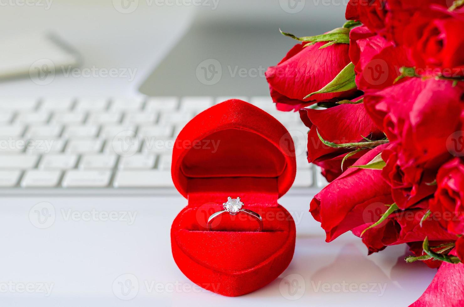 Gift box with diamond ring and red roses on working desk to surprise on engagement in Valentine day. photo