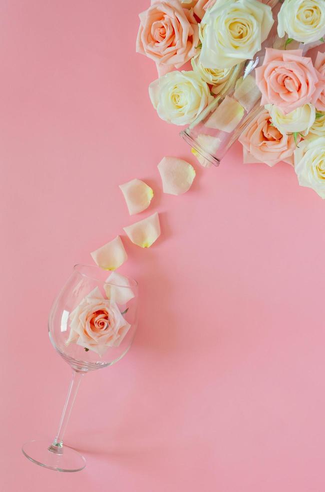 Pink rose in wine glass with the petals from the bottle put on pink background for Valentine day. Flat lay top view background concept. photo