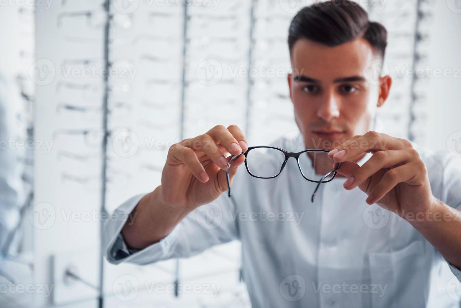 foto enfocada de gafas nuevas que sostiene el joven oculista en el interior