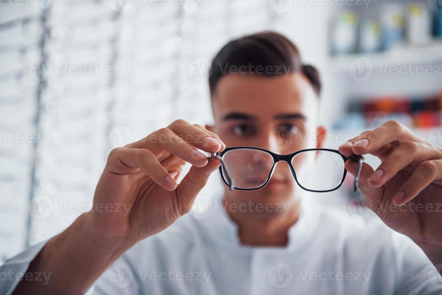 foto enfocada de gafas nuevas que sostiene el joven oculista en el interior