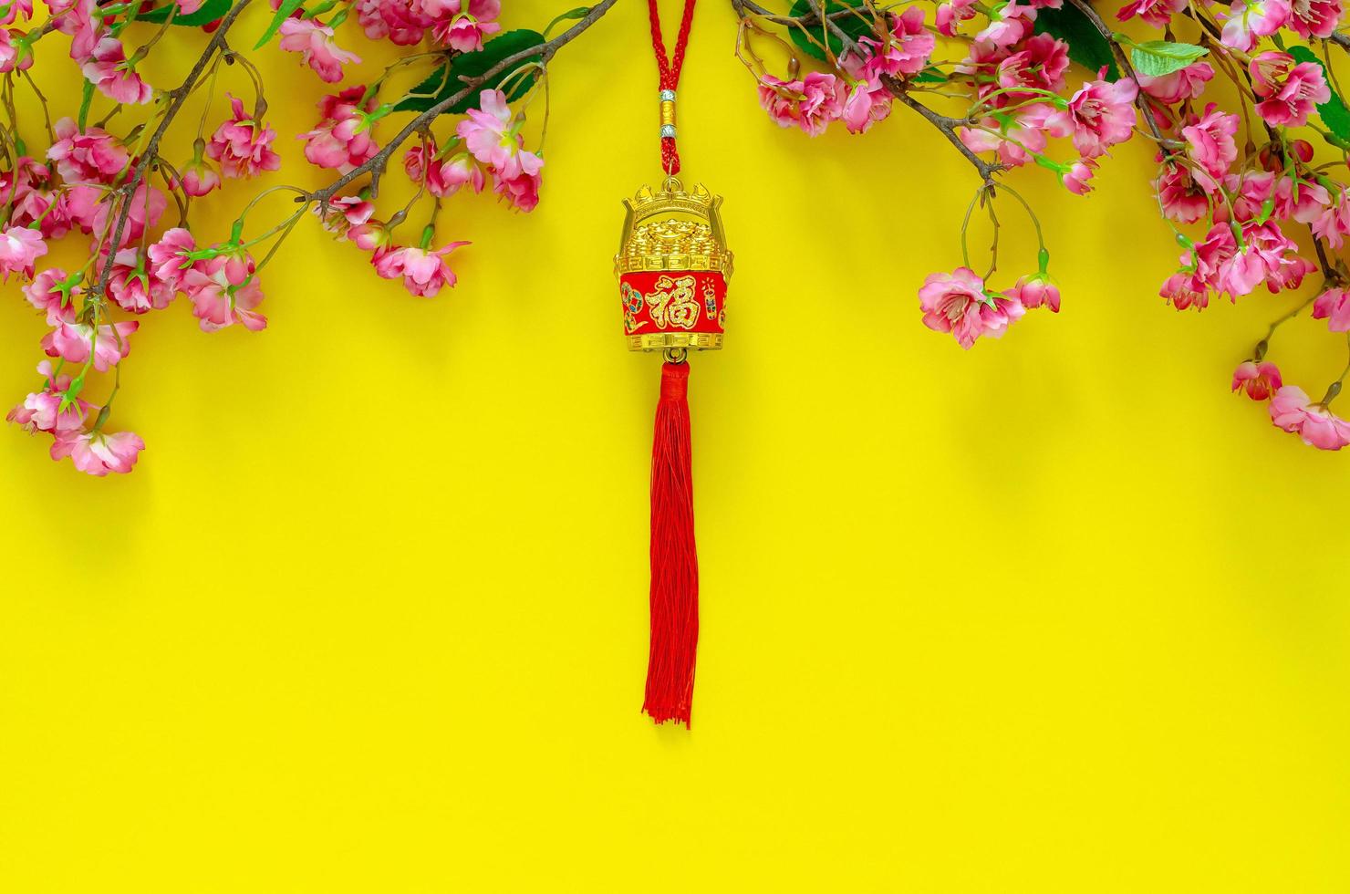 Hanging pendant for Chinese new year ornament meaning of word is wealth with Chinese blossom flowers on yellow background. photo