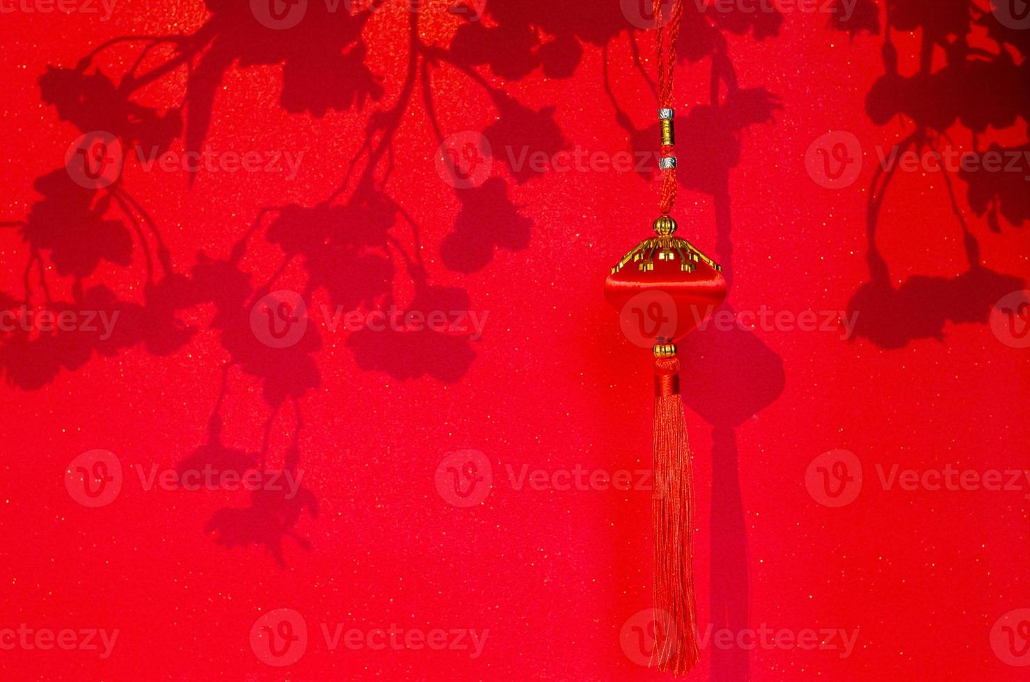 Hanging pendant for Chinese new year ornament with shadow of peach blossom flowers on red glitter paper background. photo