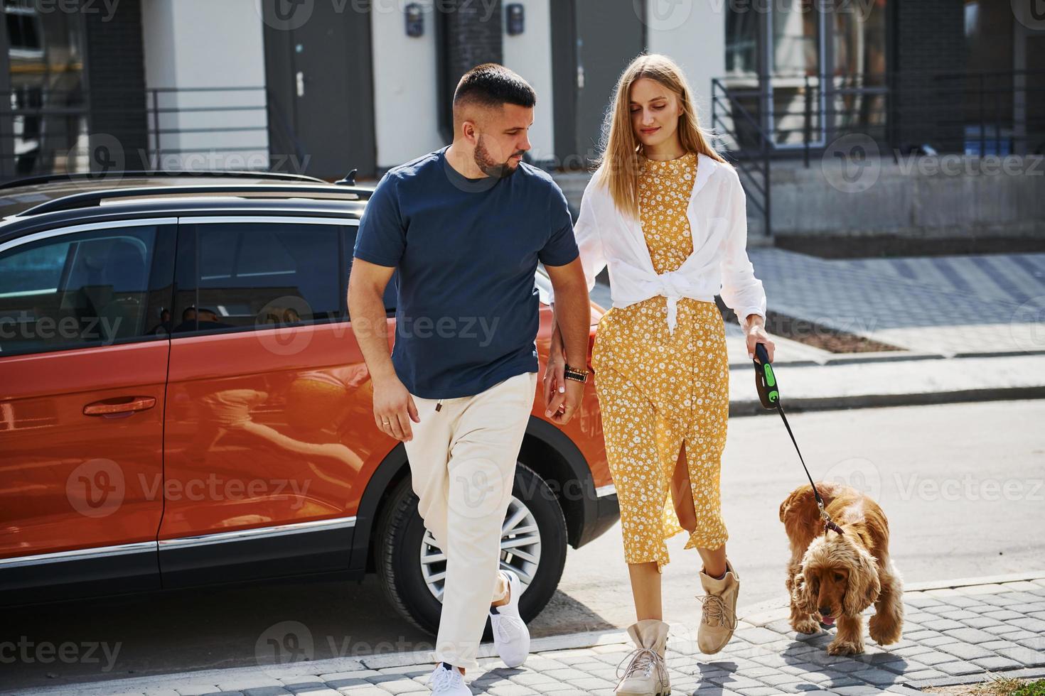 Lovely couple have a walk together with dog outdoors near the car photo