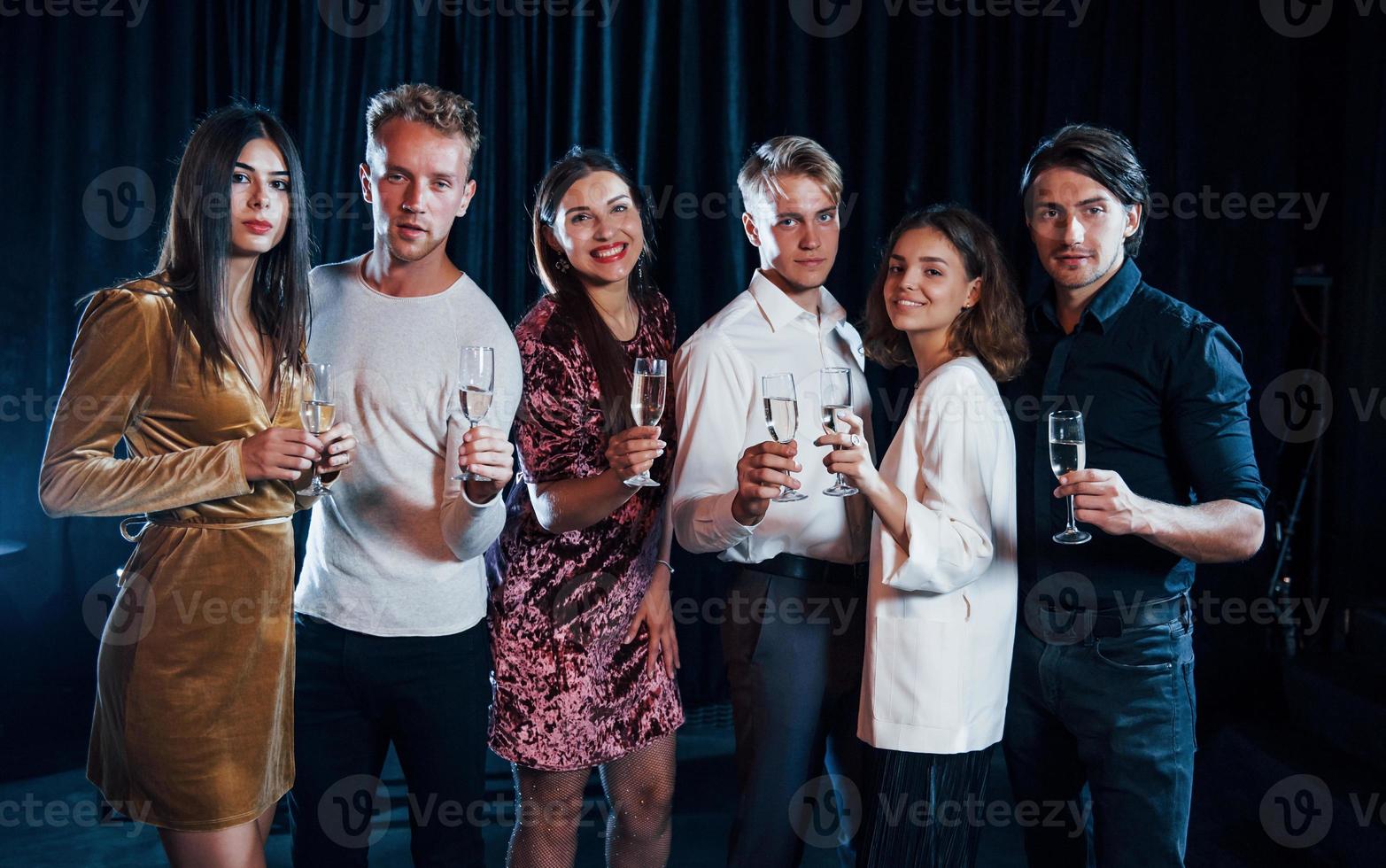 Group of friends in festive clothes have party indoors together photo