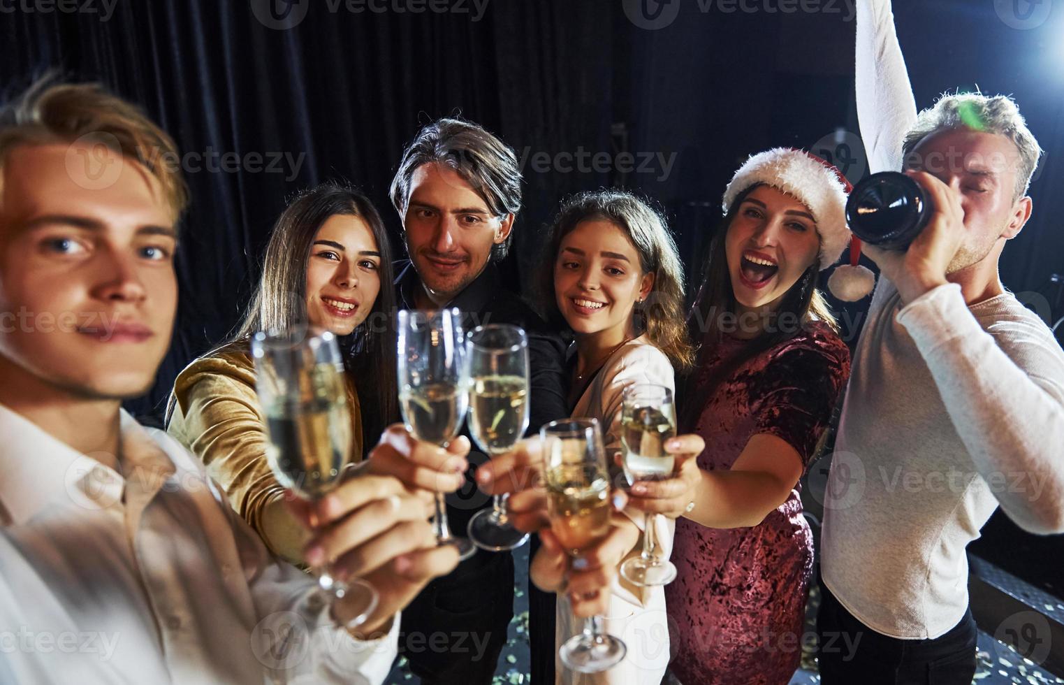 toma autofoto grupo de amigos alegres celebrando el año nuevo en el interior con bebidas en las manos foto