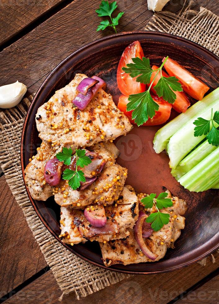 Sliced pork grilled with vegetables on ceramic brown plate. photo