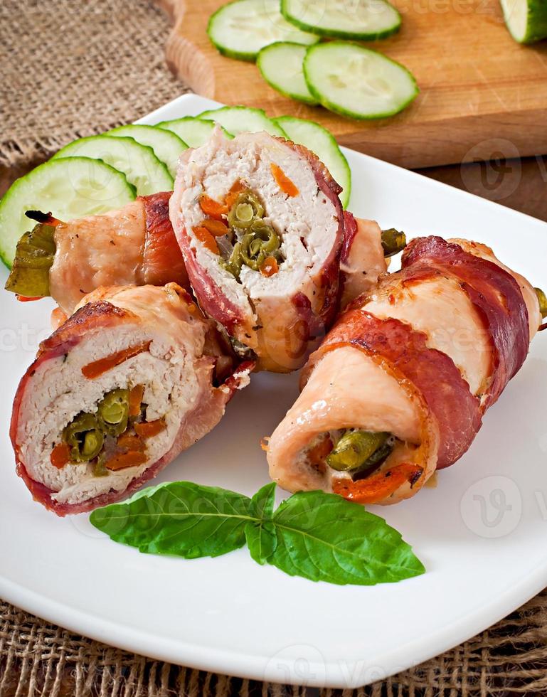 Delicious chicken rolls stuffed with green beans and carrots wrapped in strips of bacon photo