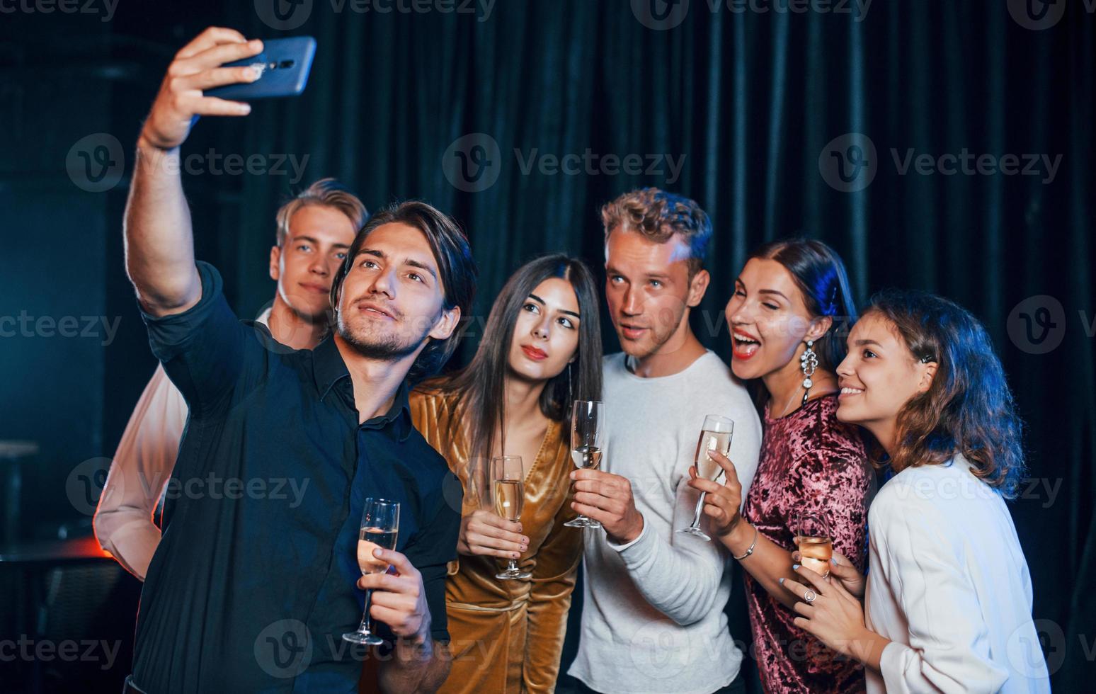 Group of cheerful friends celebrating new year indoors with drinks in hands photo