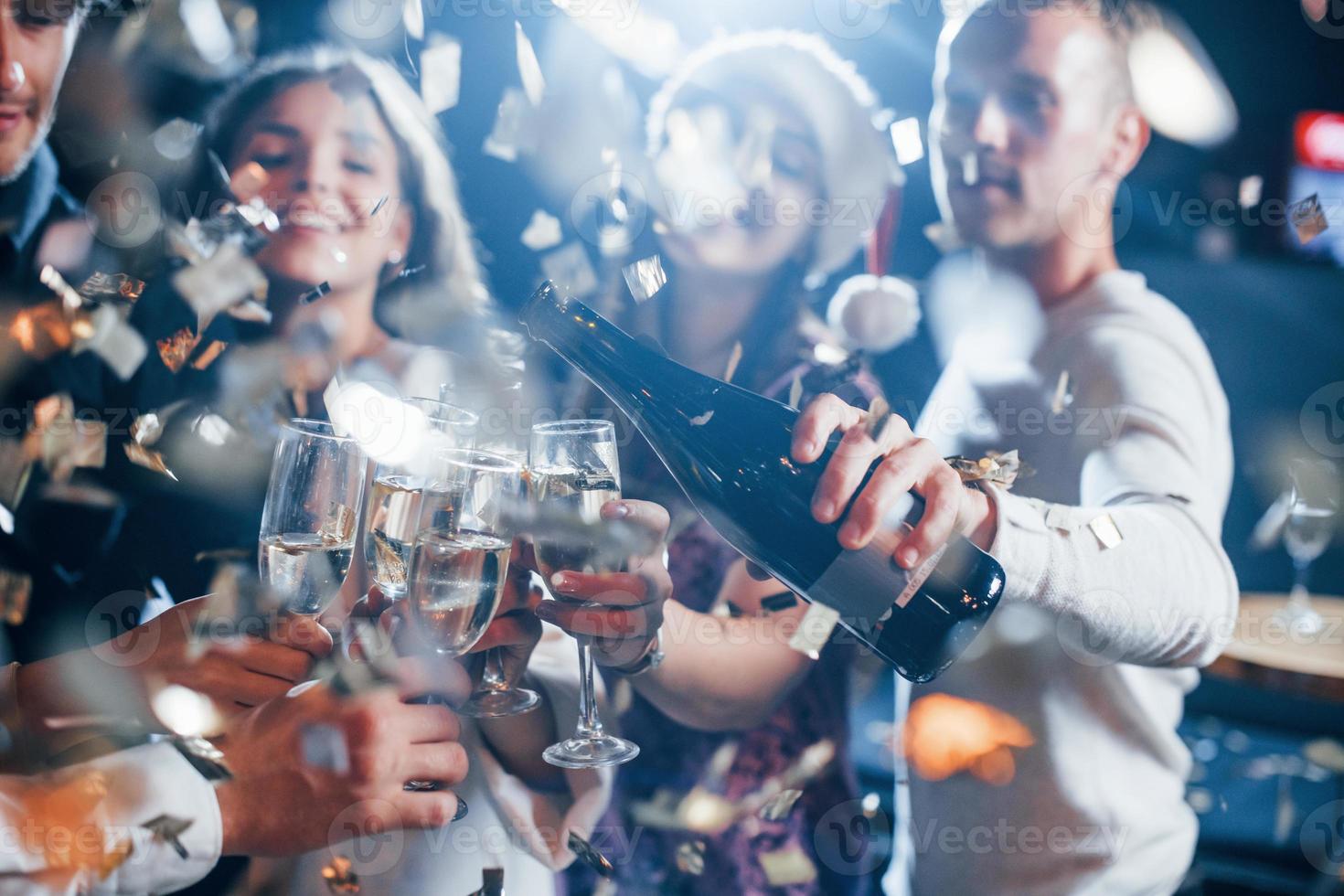 grupo de amigos alegres celebrando el año nuevo en el interior con bebidas en las manos foto