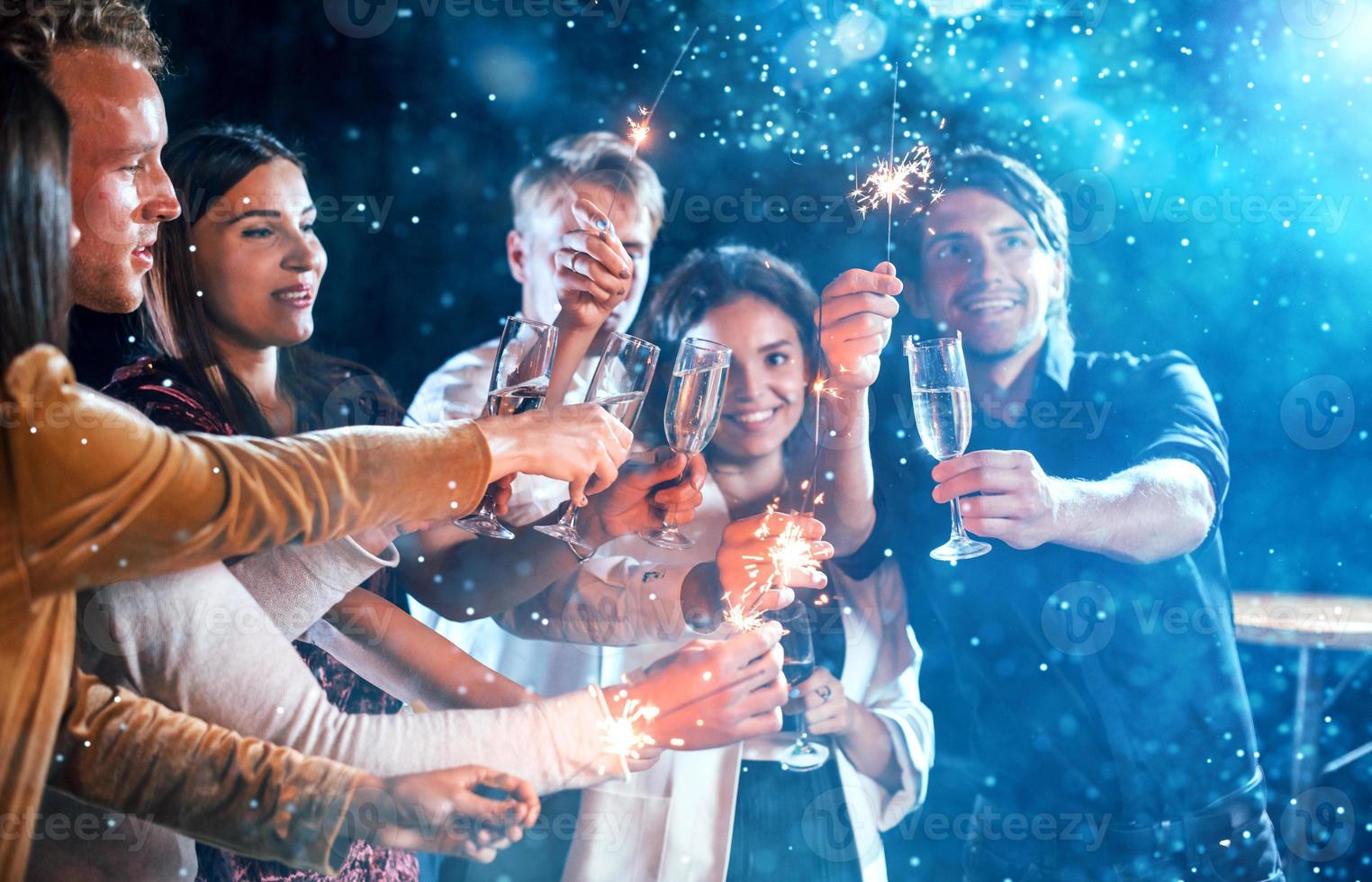 grupo de jóvenes alegres tienen fiesta y celebran el año nuevo en el interior foto