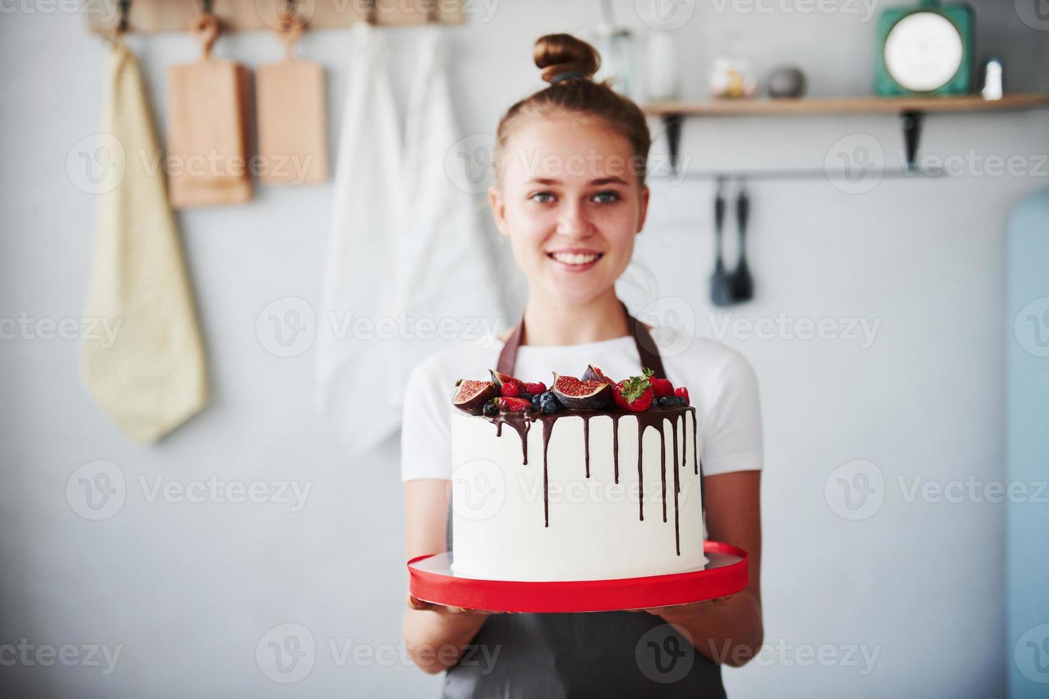 Woman stands indoors in the kitchen with homemade pie photo