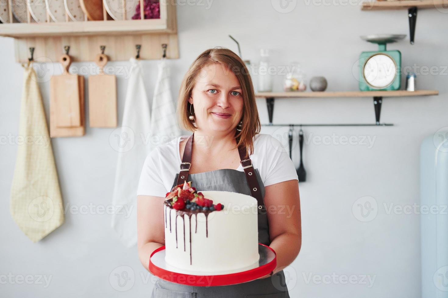 mujer se encuentra en el interior de la cocina con pastel casero en sus manos foto